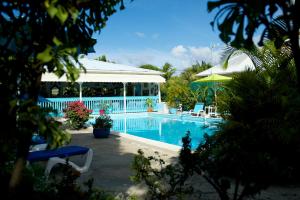 una piscina junto a una casa con un edificio en Hotel Cap Sud Caraibes en Le Gosier