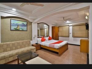 艾哈迈达巴德Darshan Hotel & Restaurant的一间酒店房间，里面有一张床和一张沙发