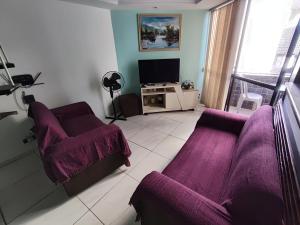 a living room with two purple couches and a tv at Apartamento dúplex em frente ao mar de Pajuçara in Maceió