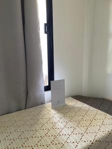 a white speaker sitting on a bed in front of a window at Thomasita's Homestay in General Luna
