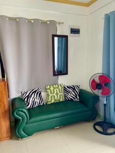 a green couch in a living room with a mirror at Thomasita's Homestay in General Luna