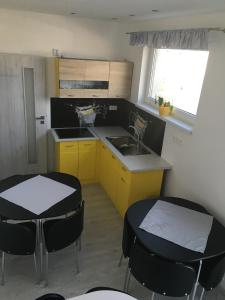 a kitchen with two tables and a sink and yellow cabinets at Mini Motel in Budimír