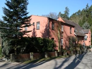 a pink house with a fence and a tree at Pension & Gasthaus Kattenstieg in Heiligengrabe