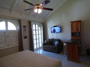 a bedroom with a bed and a couch and a ceiling fan at Beach Studio 30 in Ocho Rios