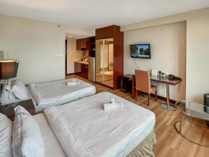 una camera d'albergo con due letti e un tavolo di Royal Crown Scsp KK CBD near Imago a Kota Kinabalu Altre 9 foto