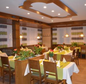 a restaurant with tables and chairs with flowers on them at Hotel Königsteiner Hof in Königstein in der Oberpfalz