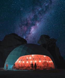 ワディ・ラムにあるRum ROZA Luxury Campの夜、ドーム型の建物の外に立っている二人