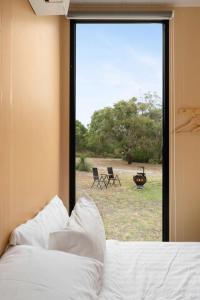 CashmoreにあるBushland Haven by Tiny Awayのベッドルーム1室(ベッド1台、椅子付きの窓付)