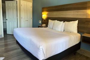 Un dormitorio con una gran cama blanca con cabecero de madera. en Days Inn by Wyndham San Diego Vista, en Vista