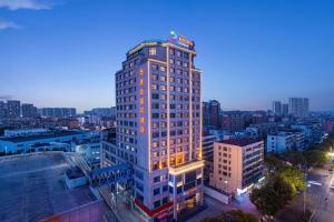 a tall building with a sign on top of it at Ramada Encore by Wyndham Jingzhou Shashi in Jingzhou