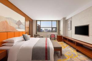 a hotel room with a bed and a flat screen tv at Ramada Encore by Wyndham Jingzhou Shashi in Jingzhou