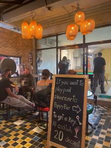 un gruppo di persone sedute in un ristorante con un cartello di Poppy hostel a Pai