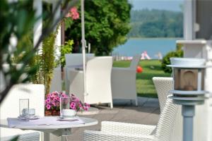 Latschach ober dem Faakerseeにあるエアレプニス ホテル アパートメンツの水辺の景色を望むパティオ(テーブル、椅子付)