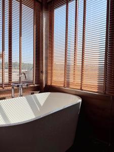 a bathroom with a tub in front of two windows at Baan Marukome Chiang Rai บ้านมารุโกเมะ เชียงราย in Ban Pa Yang (3)