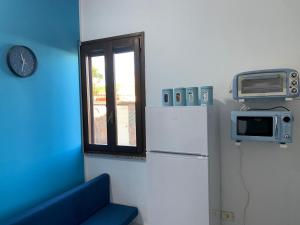a kitchen with a refrigerator and a microwave and a window at APPARTAMENTO CIELO pochi passi dal mare in Calasetta