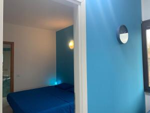 a blue bedroom with a bed and a mirror at APPARTAMENTO CIELO pochi passi dal mare in Calasetta