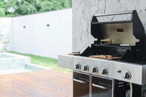 a bbq grill on a deck with a stone wall at Luxury House in Gated Community with Pool near Beaches! in Armacao dos Buzios