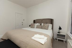 Un dormitorio con una cama grande con toallas blancas. en Charming Victorian Retreat 4BR House in Central Manchester, en Mánchester