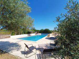 a swimming pool with chairs and a table at Chambre d'hôtes de charme, A Nosté M&P in Poussignac
