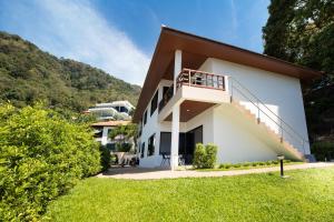 una casa blanca con balcón y césped en Baan Chom View Residences, en Kamala Beach