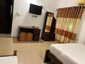 a bedroom with a bed and a tv on the wall at Canbo Hotel in Bibile