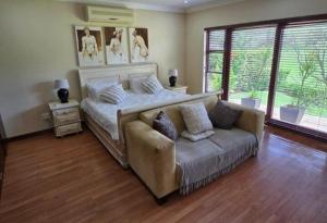 a bedroom with a bed and a couch and a window at Pecanwood Estate Dream views 4 bedroom Villa with pool in Hartbeespoort +56 photos