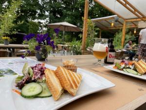two plates of food on a table with a glass of beer at Bosmuis Ardennen, Genieten in de bossen in chalet 226 in Durbuy