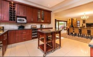 a kitchen with wooden cabinets and a dining room at Pecanwood Estate Dream views 4 bedroom Villa with pool in Hartbeespoort