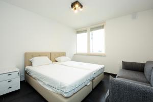 a white bedroom with a bed and a chair at Zeedijk 237 Middelkerke in Middelkerke