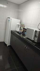 a kitchen with a counter with a microwave and a refrigerator at Hostel Eldorado Contagem in Contagem