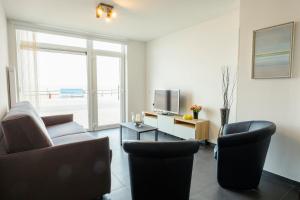a living room with a couch and chairs and a television at Zeedijk 237 Middelkerke in Middelkerke