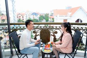 a man and woman sitting on a balcony with a cake at Legacy Hotel in Kỳ Vĩ