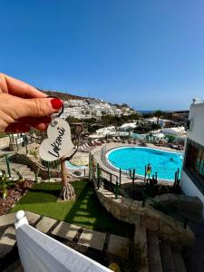 una mano sosteniendo una llave de la casa con vistas a la piscina en Sunny Monaco Puerto Rico, en Mogán