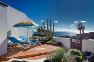 une terrasse avec des chaises et un parasol, et l'océan dans l'établissement Casa Nautilus, à Charco del Palo