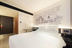天津市にあるCitiGO Hotel Tianjin Binjiang Roadのベッドルーム1室(白いベッド1台、ライティングウォール付)