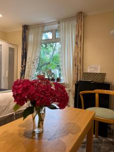 a vase filled with red flowers on a wooden table at 3 Bed Cottage Retreat - Private Garden & Parking in Orpington +11 photos