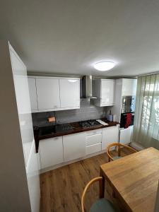 a kitchen with white cabinets and a wooden table at 3 Bed Cottage Retreat - Private Garden & Parking in Orpington