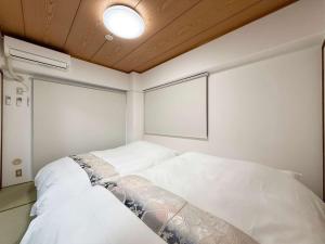 1 dormitorio con 2 camas blancas y techo en Residence Yu by b hotel - Relaxing 2BR Near City Center Dining & Kitchen, en Hiroshima