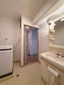Un baño blanco con lavabo y espejo. en Residence Yu by b hotel - Relaxing 2BR Near City Center Dining & Kitchen, en Hiroshima