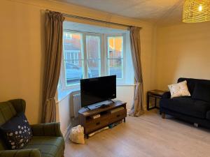 un salon avec une télévision à écran plat et un canapé dans l'établissement Theos Nook 4 Bedroom House, Sleeps 6, à Hopton on Sea