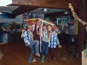 een man en drie meisjes zitten onder een paraplu bij Smarties Surf Lodge in Newquay