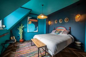 a bedroom with blue walls and a bed and a table at L ' hacienda in Blendecques