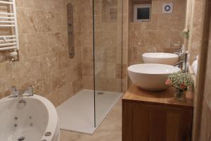 La salle de bains est pourvue d'une baignoire, d'un lavabo et d'une douche. dans l'établissement Ashford House 2 bedroom Apartment 'outdoor bathing tub', à Fylingthorpe
