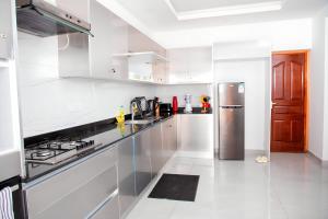 a kitchen with white cabinets and a stainless steel refrigerator at Luxury 3br Ensuite Apt in Prestigious Nyali in Mombasa