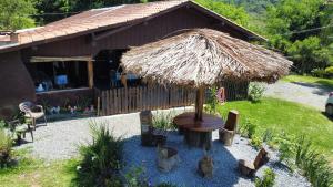 a large straw umbrella in front of a house at Sítio Rota 77 in Canelinha