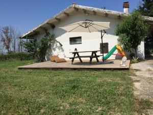 a picnic table with an umbrella and a playground at Casale le Querce in Cellino Attanasio