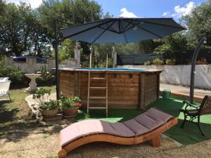 a pool with an umbrella and a bench with a table at Casale le Querce in Cellino Attanasio
