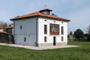 a small white house with a red roof at Casa Vacacional el Xuncu in Posada de Llanes