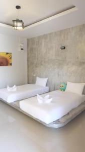 deux lits dans une chambre aux murs blancs dans l'établissement Lullaby Boutique Resort, à Thap Sakae