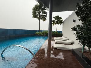 una piscina con sedie e palme in un edificio di Eaton Premier Suite KLCC a Kuala Lumpur